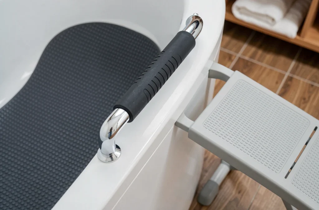 Détail des accessoires de sécurité pour baignoire PMR : tapis antidérapant, barre d'appui et siège de transfert